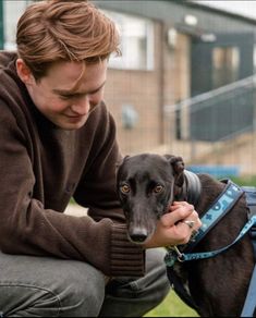 a man petting a dog on the head with a leash around it's neck