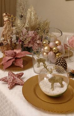 a table topped with plates and vases filled with christmas decorations on top of a white table cloth