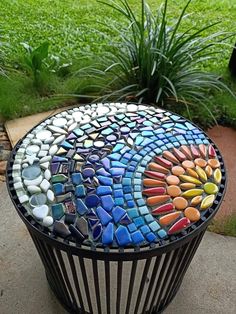 a colorful mosaic table sitting on top of a cement slab in front of some grass