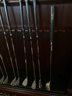 several golf clubs are lined up on a shelf in a room with wood paneling