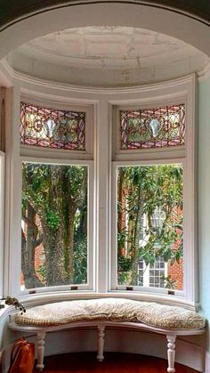 a window seat in the corner of a room with stained glass windows and wood flooring