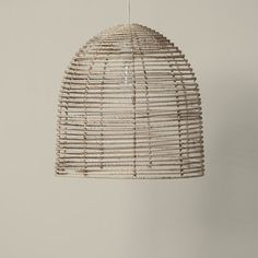 a hanging light made out of wicker with a white cord attached to the ceiling