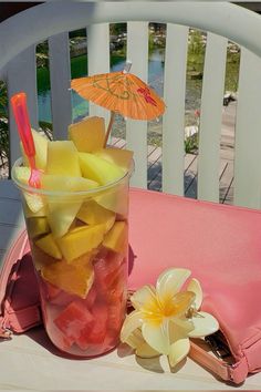 a glass filled with fruit sitting on top of a table next to a pink purse