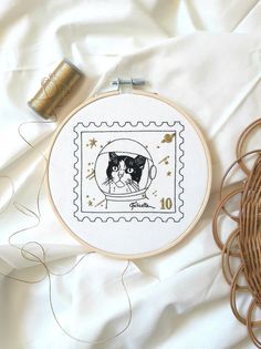 a cross stitch pattern with a cat in a bubble on top of a white sheet