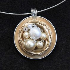 a silver pendant with pearls in it on a black background