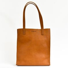 Tall market tote crafted in pebbled vegetable tanned leather and an unlined interior. The sleek minimal design makes it a great everyday bag for work, school or a visit to the farmers market. It features reinforced bottom support and large interior pocket to keep your keys and phone close by. - Pebbled Full Grain Italian Vegetable-Tanned leather - Unlined Interior - Includes 1 large interior pocket - Reinforced bottom support - Ethically Handcrafted in the Dominican Republic Classic Brown Shoulder Bag For Everyday, Everyday Cognac Textured Leather Bag, Modern Everyday Bag With Smooth Grain, Everyday Brown Textured Leather Bag, Modern Everyday Shoulder Bag In Vegetable Tanned Leather, Everyday Cognac Shoulder Bag With Smooth Grain, Classic Brown Shoulder Bag For Daily Use, Everyday Smooth Grain Tote Shoulder Bag, Minimalist Everyday Bag With Smooth Grain