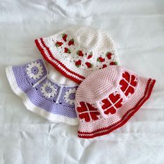 three crocheted hats sitting on top of a bed