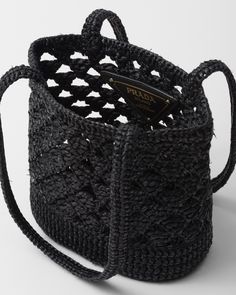 a black crocheted basket with two handles on the front and one handle in the back