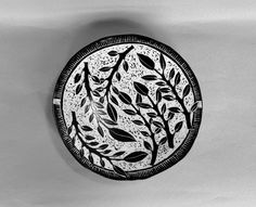 a black and white photo of a plate with leaves on it's side, against a gray background