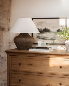 a lamp on top of a dresser next to a painting