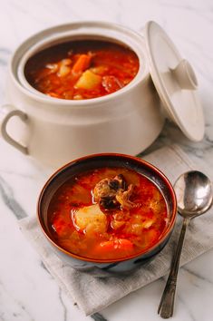 two bowls of soup on a table with spoons