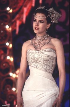 a woman in a white dress wearing a necklace and tiara with jewels on her head