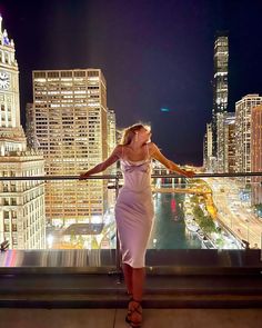 a woman standing on top of a building with her arms outstretched in front of the camera