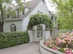 a white house surrounded by flowers and trees