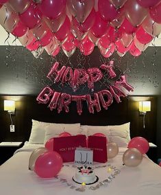 a bed with pink and red balloons hanging from the ceiling