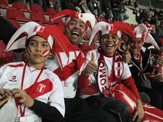 some fans are sitting in the stands at a sporting event with their faces painted red and white