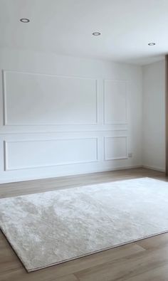 an empty room with white walls and wood floors