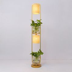 a plant stand with three plants in glass vases on it and a lamp hanging from the side