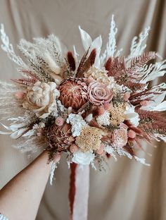 a bridal bouquet is being held by someone's hand