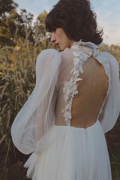 the back of a woman's wedding dress with sheer white fabric and flowers on it