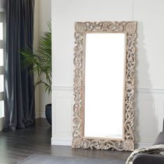 a large mirror sitting on top of a wooden floor next to a couch in a living room