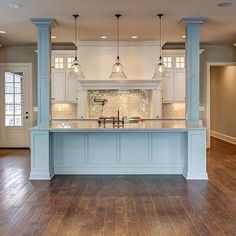 a large kitchen with an island in the middle and two pendant lights hanging from the ceiling