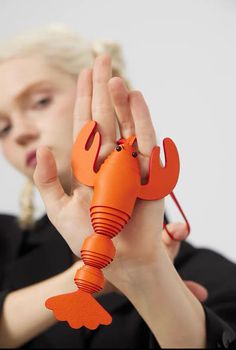 a woman holding up an orange plastic lobster