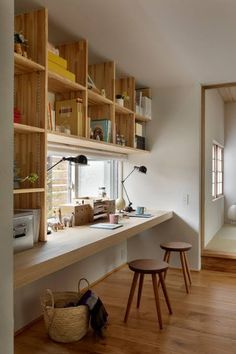 a room with wooden shelves and stools on the floor next to a desk in front of a window