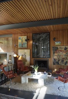 a living room filled with lots of furniture and paintings on the wall next to a fire place