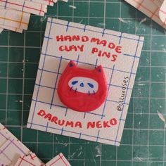 a piece of paper that has been made to look like a red monster with the words handmade clay pins written on it