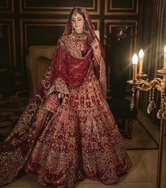 a woman in a red and gold bridal gown standing next to a candlelight chandelier