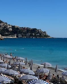 many umbrellas are set up on the beach as people swim in the blue water