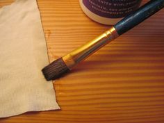 a brush sitting on top of a piece of cloth next to a bottle of paint