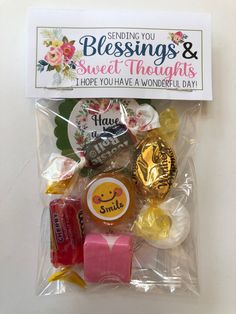 some candy and candies are in a plastic bag on a white surface with a sign that says sending you blessing & sweet thoughts