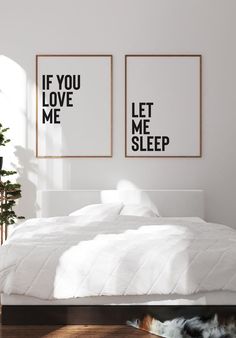 two black and white posters on the wall above a bed in a room with hardwood floors