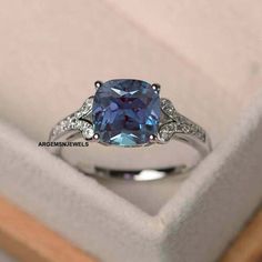 an engagement ring with a blue topazte surrounded by white diamonds in a box