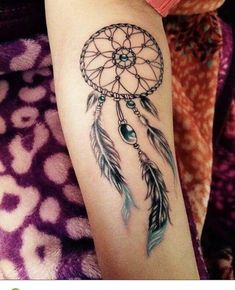 a woman's leg with a tattoo on it that has a dream catcher and beads