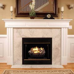 a fire place in a living room with a mirror above it and candles on the mantle