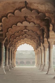 an archway in the middle of a building with columns and arches on both sides, leading into