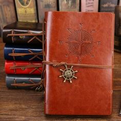 a brown leather book with a compass on the cover and other books in the background