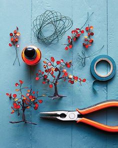 scissors, wire and other crafting items on a blue surface with red berries in the center