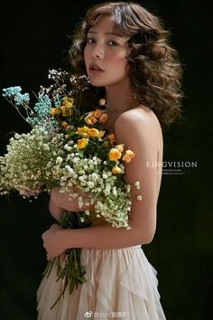 a woman holding a bouquet of flowers in her hands