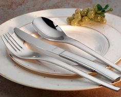 a white plate topped with silverware and grapes