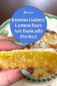 a hand holding a piece of lemon bar on top of a white and green plate