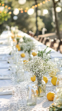 a long table with lemons and baby's breath in mason jars on it