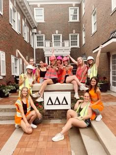 a group of young women sitting on top of steps in front of a brick building