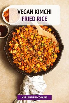 a pan filled with fried rice next to a bowl of sauce and a wooden spoon