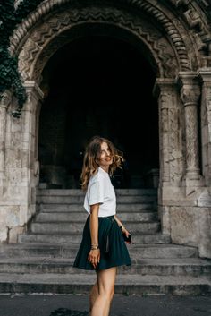 a woman in white shirt and black skirt standing on steps