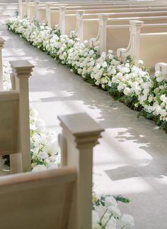 white flowers are lined up along the side of pews