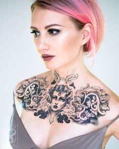 a woman with pink hair and tattoos on her chest is looking at the camera while wearing a grey dress